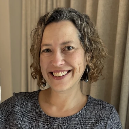 Image of smiling face with curly brown hair and a blue plaid dress.